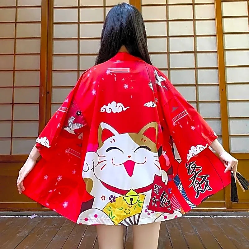 Czerwone japońskie haori damskie z dużym motywem kota szczęścia Maneki-neko i żurawiami na plecach, widok z tyłu w tradycyjnym wnętrzu.