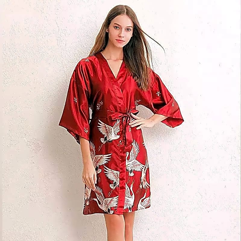 Eleganckie czerwone kimono satynowe z wzorem japońskich żurawi prezentowane przez modelkę.