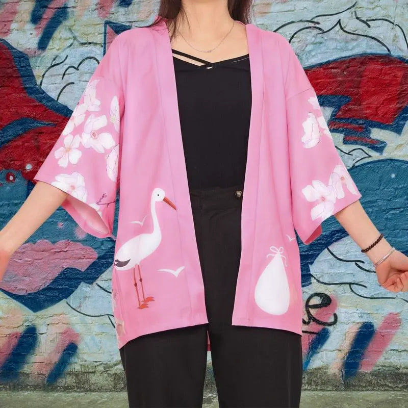 Stylowe japońskie haori damskie w kolorze różowym, z motywami żurawi i kwitnących wiśni, widok z przodu na modelce.