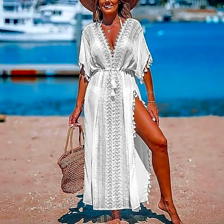 Białe długie kimono plażowe w stylu boho z koronką i frędzlami, idealne na lato, prezentowane na modelce na plaży.