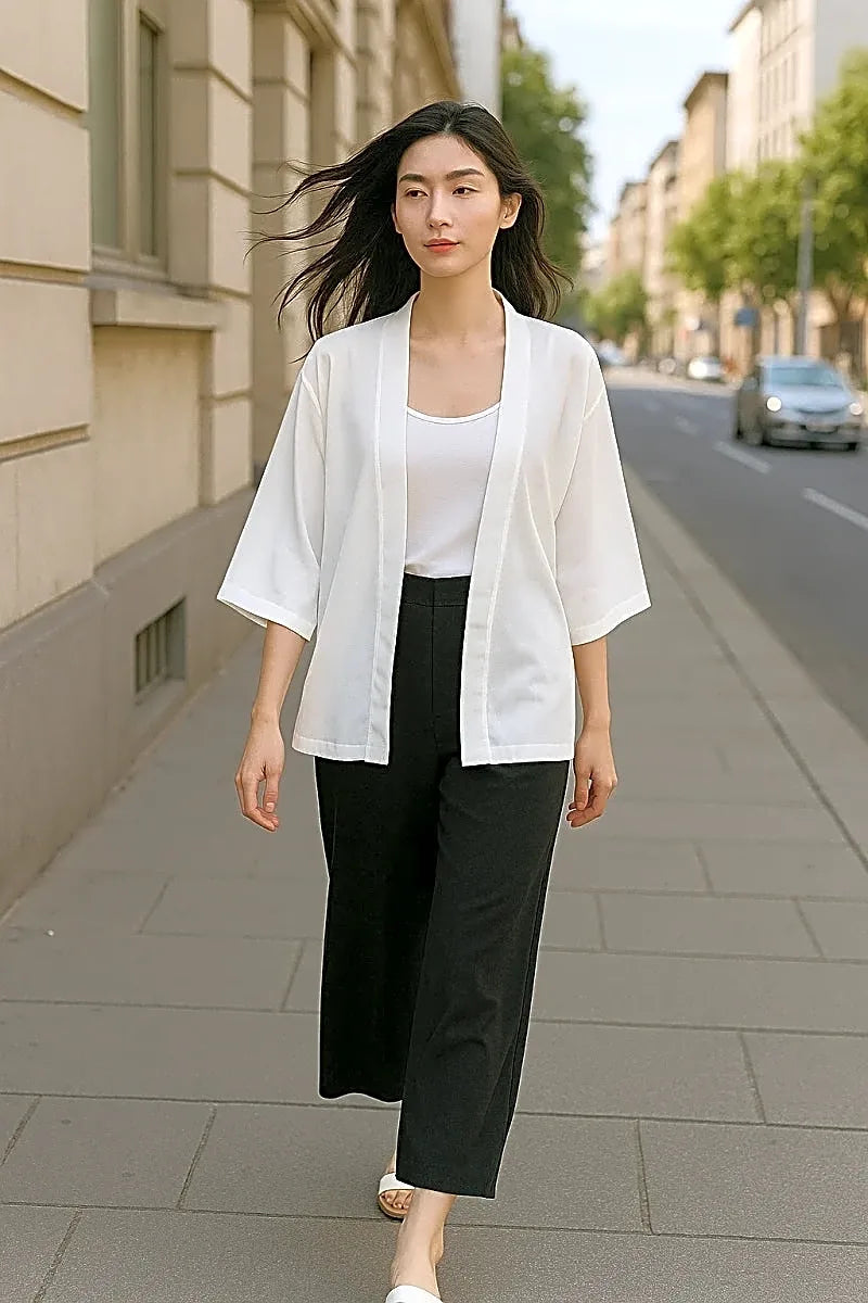 Białe krótkie kimono damskie o minimalistycznym kroju, idealne na lato, prezentowane na modelce w miejskim otoczeniu.