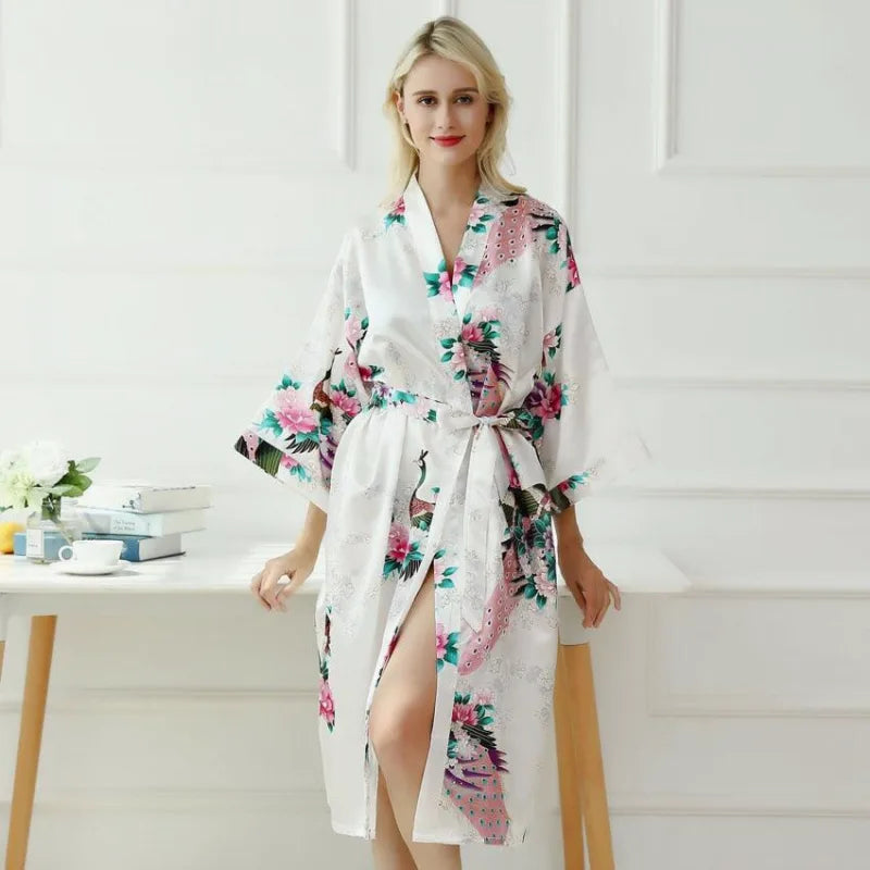 Biały satynowy szlafrok kimono damski z wzorem pawi i kwiatów, elegancko prezentowany na modelce.