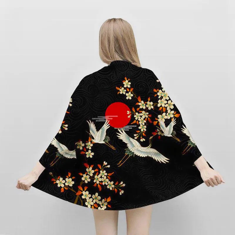 Czarne kimono damskie z japońskimi żurawiami, kwiatami i wschodzącym słońcem, widok z tyłu na modelce.