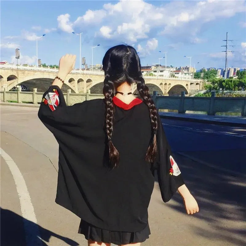 Widok z tyłu na czarne kimono damskie z szerokimi rękawami i haftem lisa kitsune, noszone przez modelkę na ulicy.