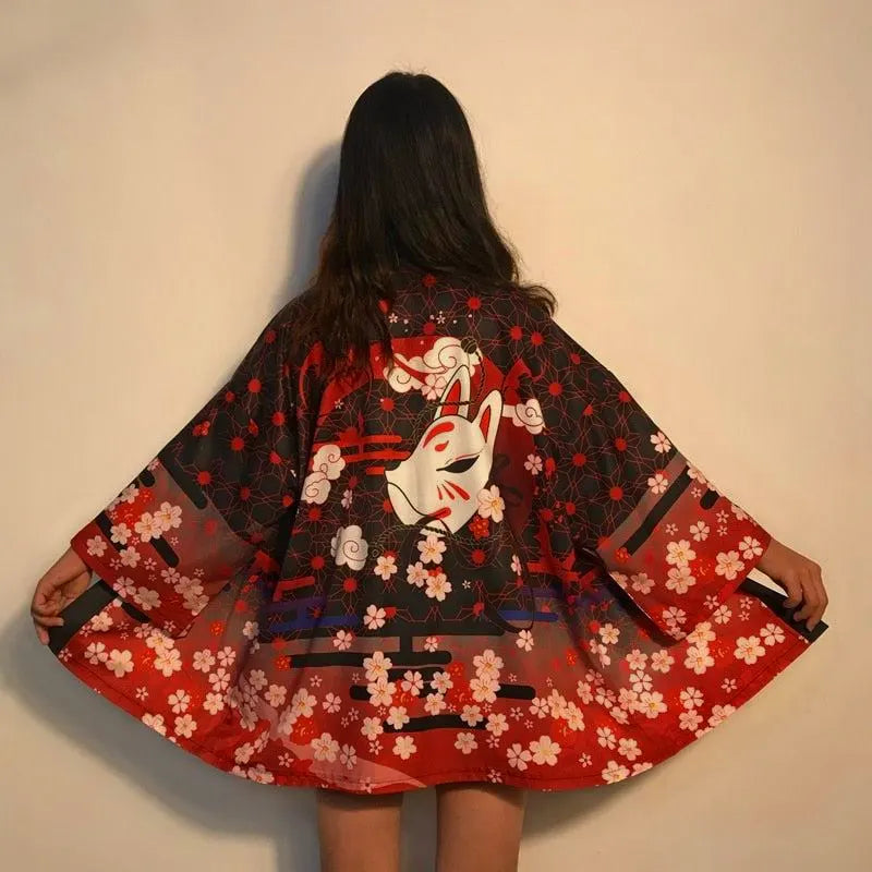 Czerwono-czarna narzutka kimono damska z japońską maską lisa Kitsune i kwiatami sakury, widok z tyłu, prezentująca pełny wzór na rozłożonym materiale.