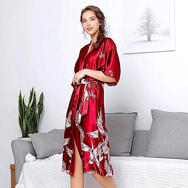 Czerwony satynowy szlafrok damski kimono z japońskimi żurawiami, modelka prezentuje elegancki fason.