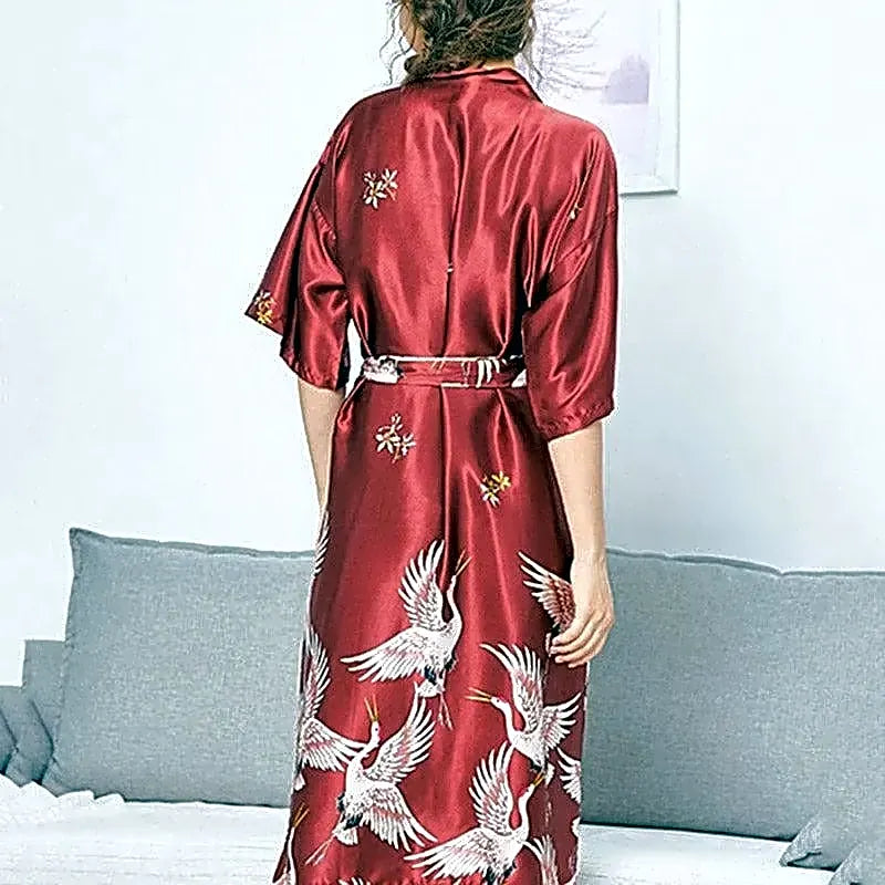 Tył czerwonego satynowego szlafroka damskiego kimono z wzorem w japońskie żurawie, widok od tyłu.