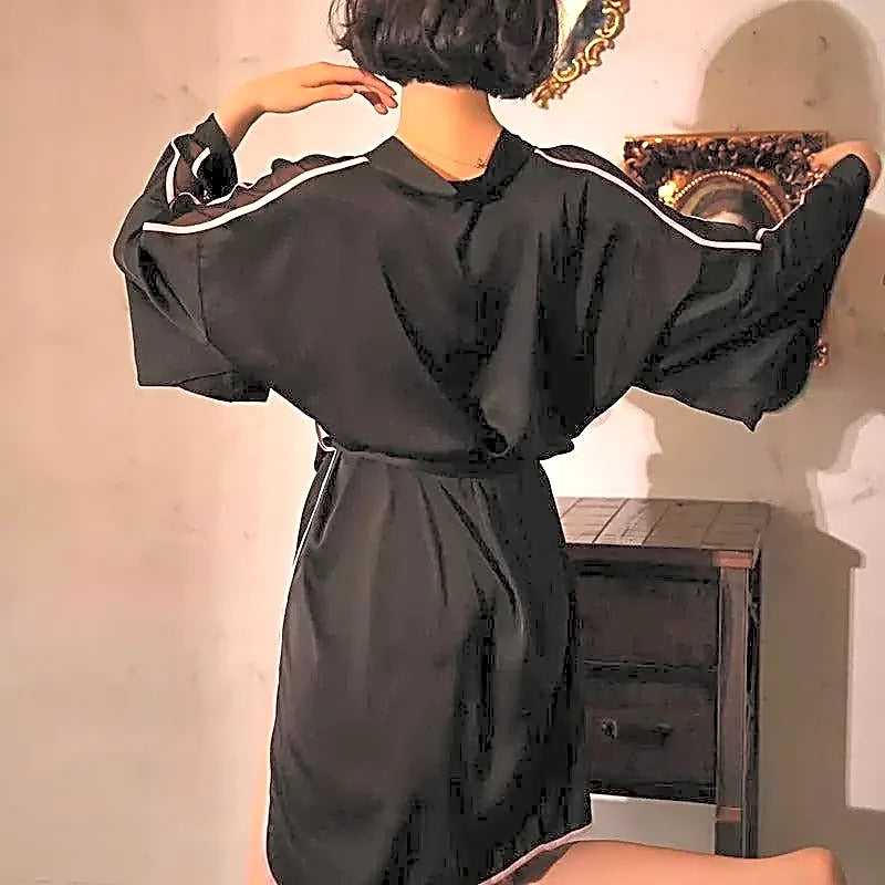 Damski szlafrok satynowy kimono w kolorze czarnym z różową lamówką i szerokimi rękawami, widok z tyłu na modelce.
