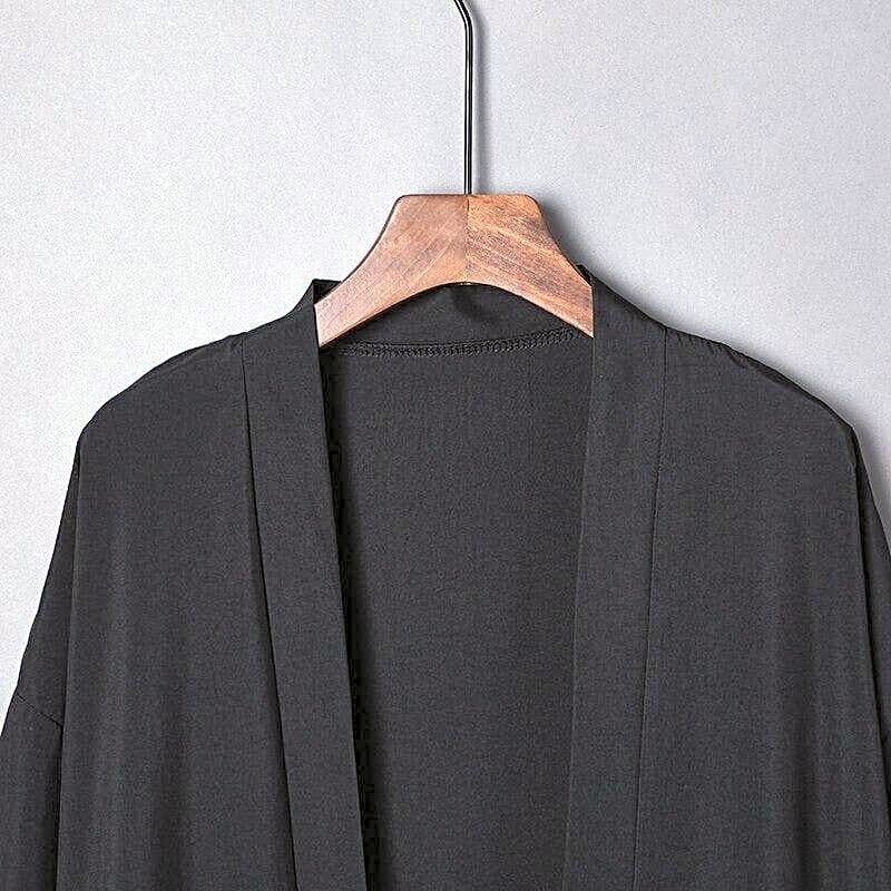 Zbliżenie na dekolt i kołnierz czarnej eleganckiej kurtki kimono damskiej, podkreślające minimalistyczny design.