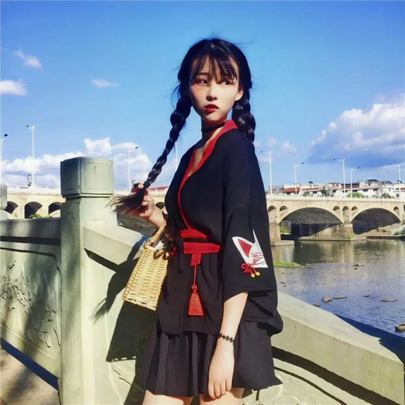 Czarne kimono damskie w stylu japońskim z wyraźnym motywem lisa kitsune na rękawie i ozdobnym czerwonym paskiem.