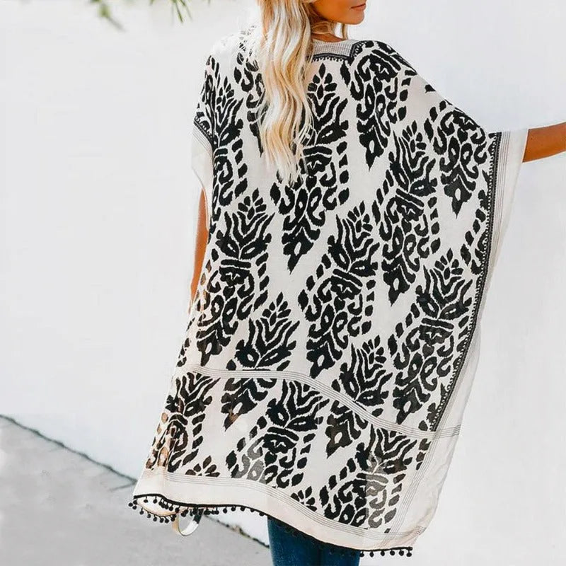 Kimono plażowe z tyłu, ukazujące pełny abstrakcyjny wzór i detale z pomponów w stylu boho, widok na modelce.