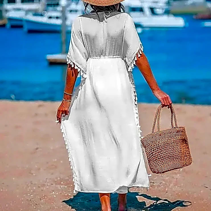 Tył białego długiego kimona plażowego boho, ukazujący swobodny krój i ozdobne frędzle, na tle morza.