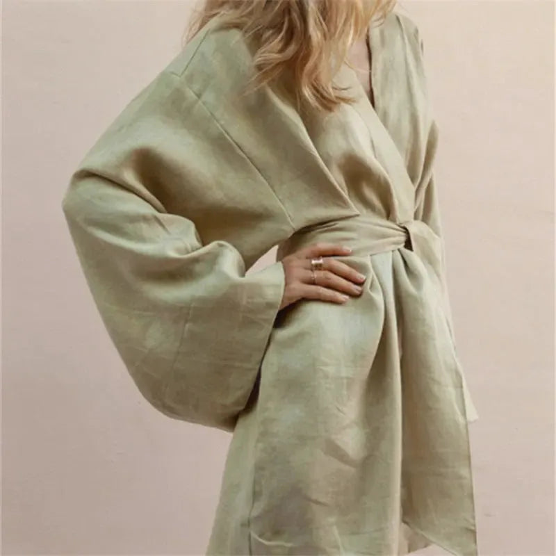 Modelka prezentująca krótkie lniane kimono w kolorze khaki, z szerokimi rękawami, ujęcie z boku.