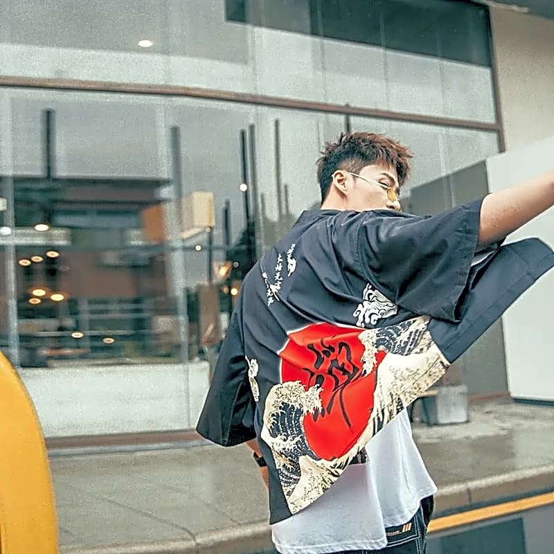 Mężczyzna prezentujący czarną narzutkę kimono haori z dużym wzorem japońskiej fali i czerwonego słońca na plecach.