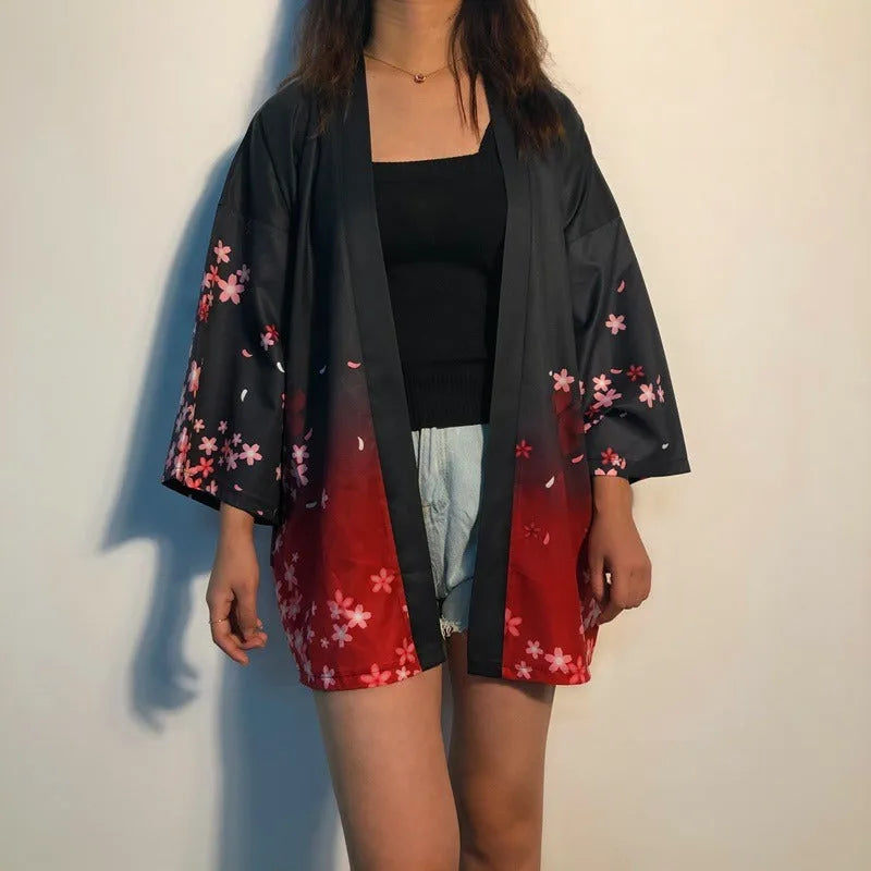 Stylowa damska narzutka kimono w odcieniach czerwieni i czerni z delikatnymi kwiatami sakury, widok z przodu na modelce, idealna do letnich stylizacji.