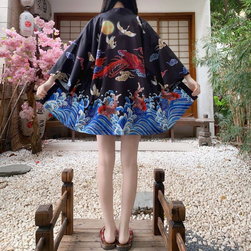 Pełna sylwetka w czarnej narzutce kimono vintage z japońskimi wzorami, w ogrodzie