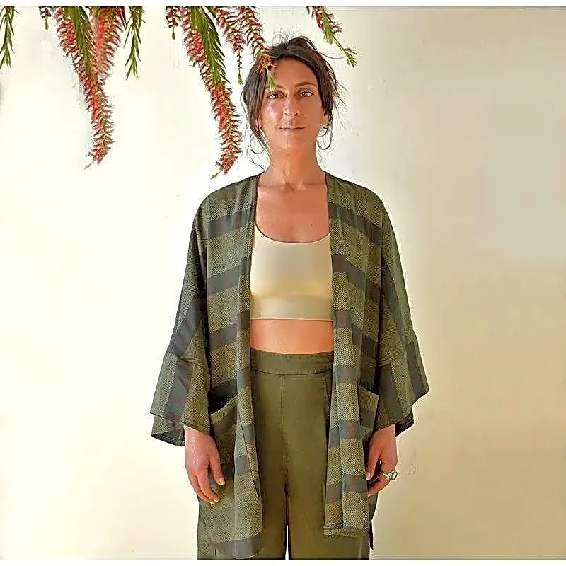 Zielony płaszcz kimono z wiskozy bawełnianej, z wyraźnym wzorem w paski i jodełkę, widok z przodu na modelce.
