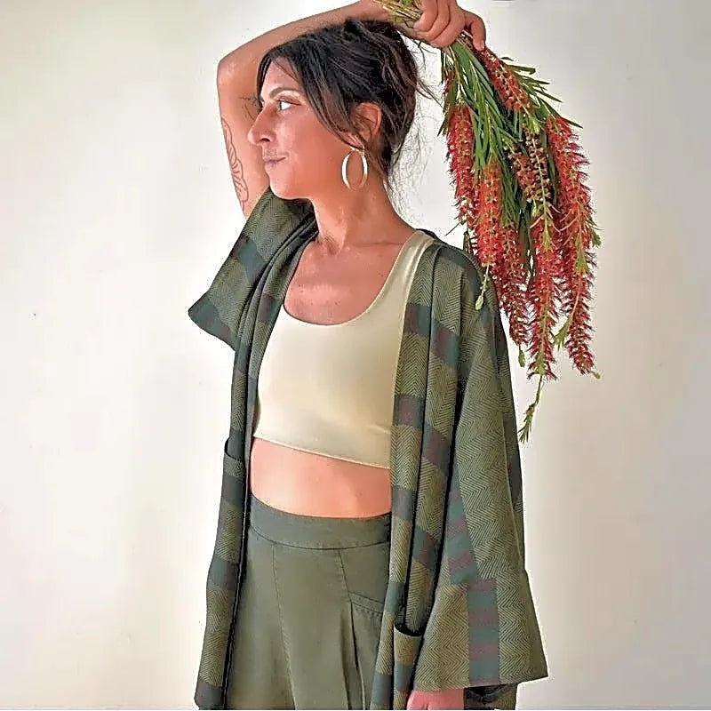 Profil modelki w zielonym płaszczu kimono, podkreślający luźny krój i detale wzoru w paski oraz jodełkę.