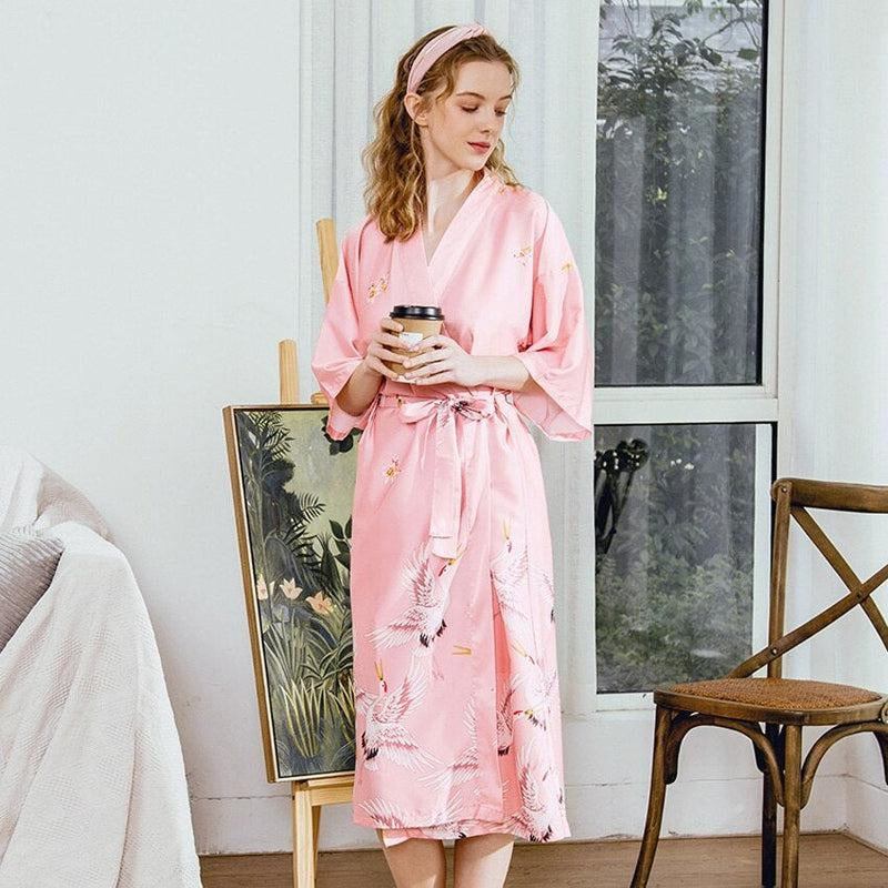 Elegancki różowy szlafrok kimono z delikatnym wzorem żurawi, noszony przez modelkę z kubkiem kawy.