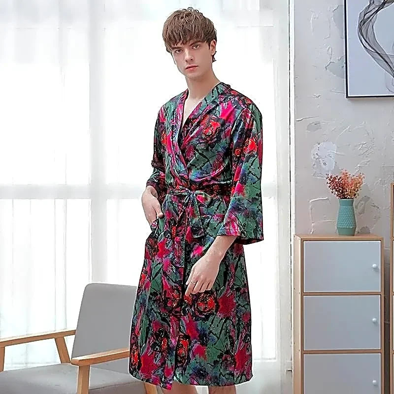 Męski satynowy szlafrok kimono z artystycznym wzorem czerwonych kwiatów na zielonym tle, prezentowany na modelu w jasnym wnętrzu.