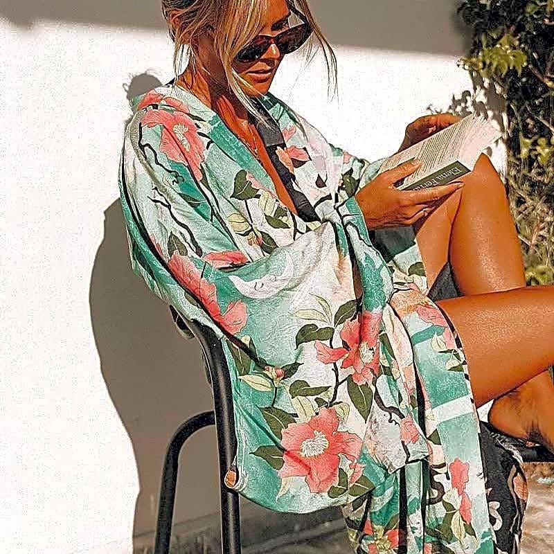 Turkusowa długa sukienka kimono z bawełny organicznej w japoński wzór z żurawiami, noszona przez modelkę czytającą książkę na zewnątrz.