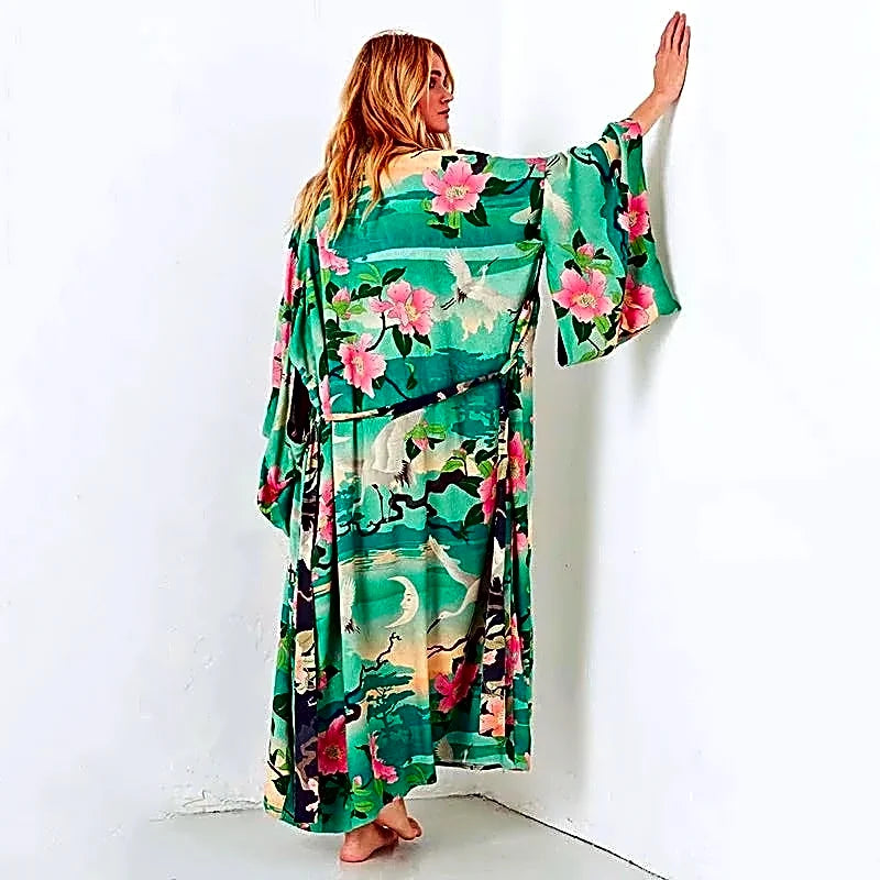 Modelka prezentująca tył turkusowej długiej sukienki kimono z bawełny organicznej, ukazującej japoński wzór z żurawiami i kwiatami.