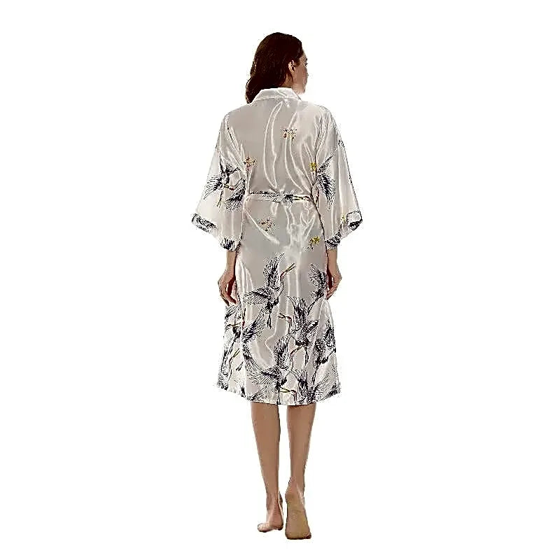 Tył białego satynowego szlafroka kimono damskiego z wzorem japońskich żurawi, elegancki fason midi.