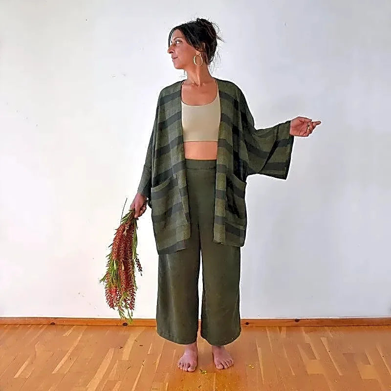 Modelka prezentująca zielony płaszcz w stylu kimono z wiskozy bawełnianej, z wzorem w paski i jodełkę, w pełnej sylwetce.