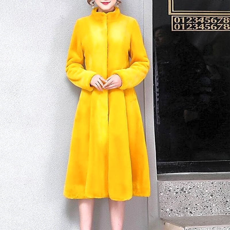 Elegancki zimowy płaszcz damski w intensywnym żółtym kolorze, wykonany z miękkiego futerka, w modnym stylu kimono, widok z przodu na modelce.